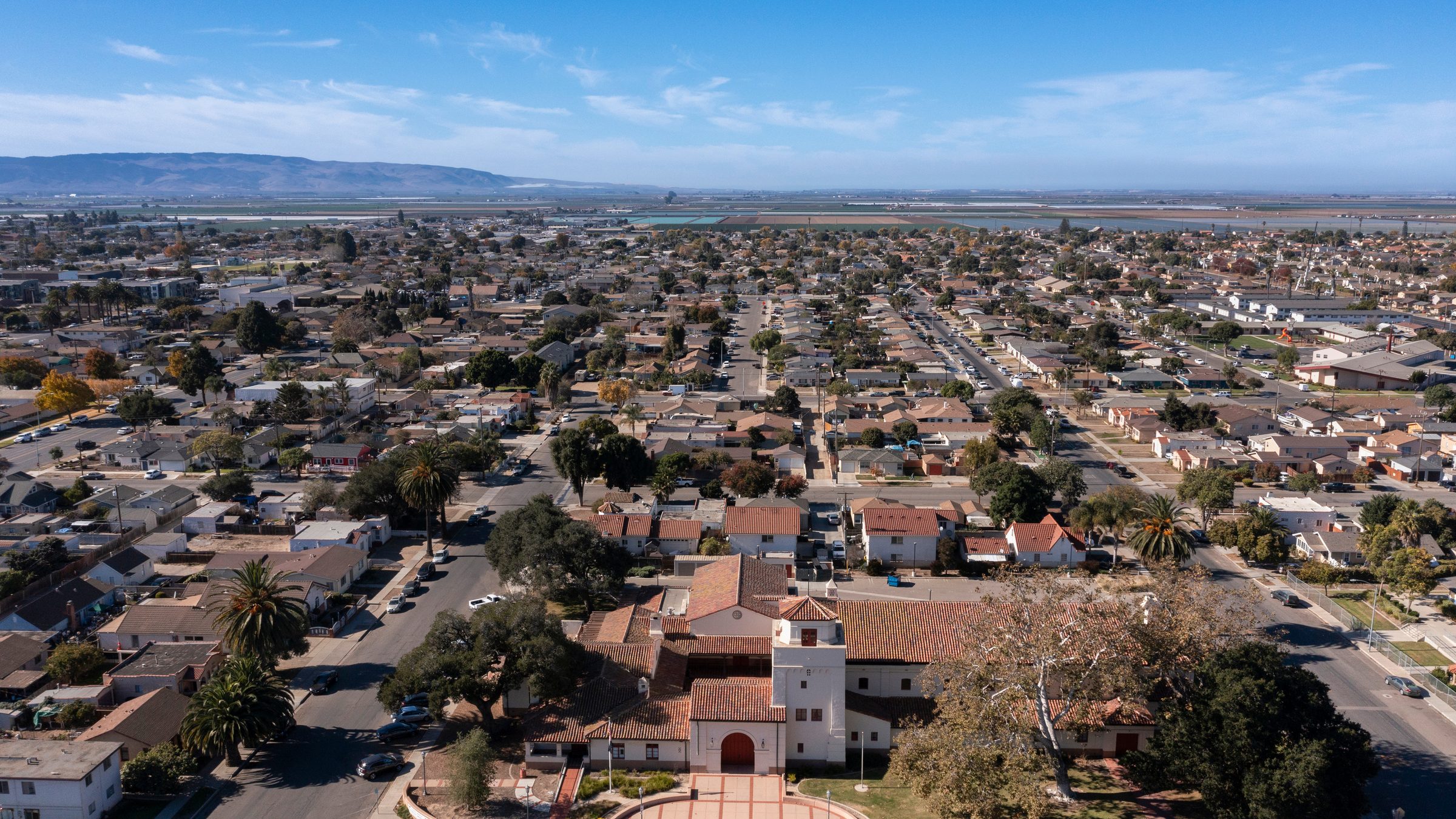 Aerial view of residential neighborhoods in Santa Maria, California, with agricultural fields and hills in the distance